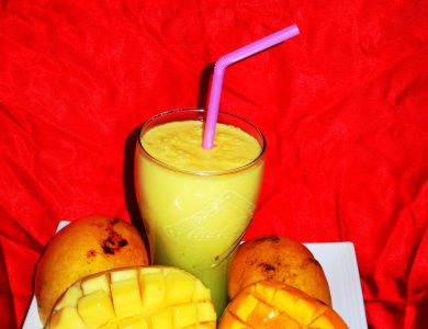 A glass of mango smoothie beside fresh mango pieces.