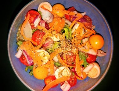 A mixed-greens salad with tomatoes, eggs, onions and carrots.