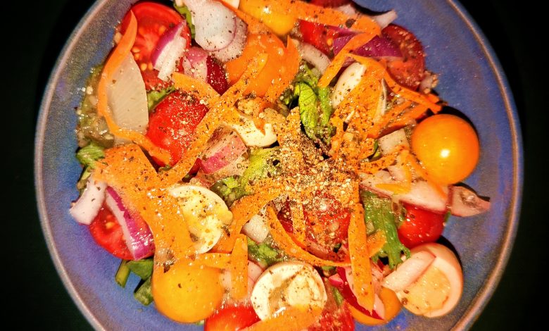 A mixed-greens salad with tomatoes, eggs, onions and carrots.